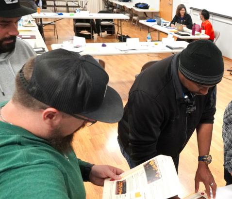 Workers reading material and sitting around a table at a training course