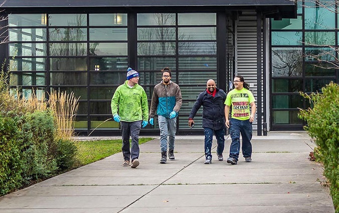 Four workers walking in front of a building